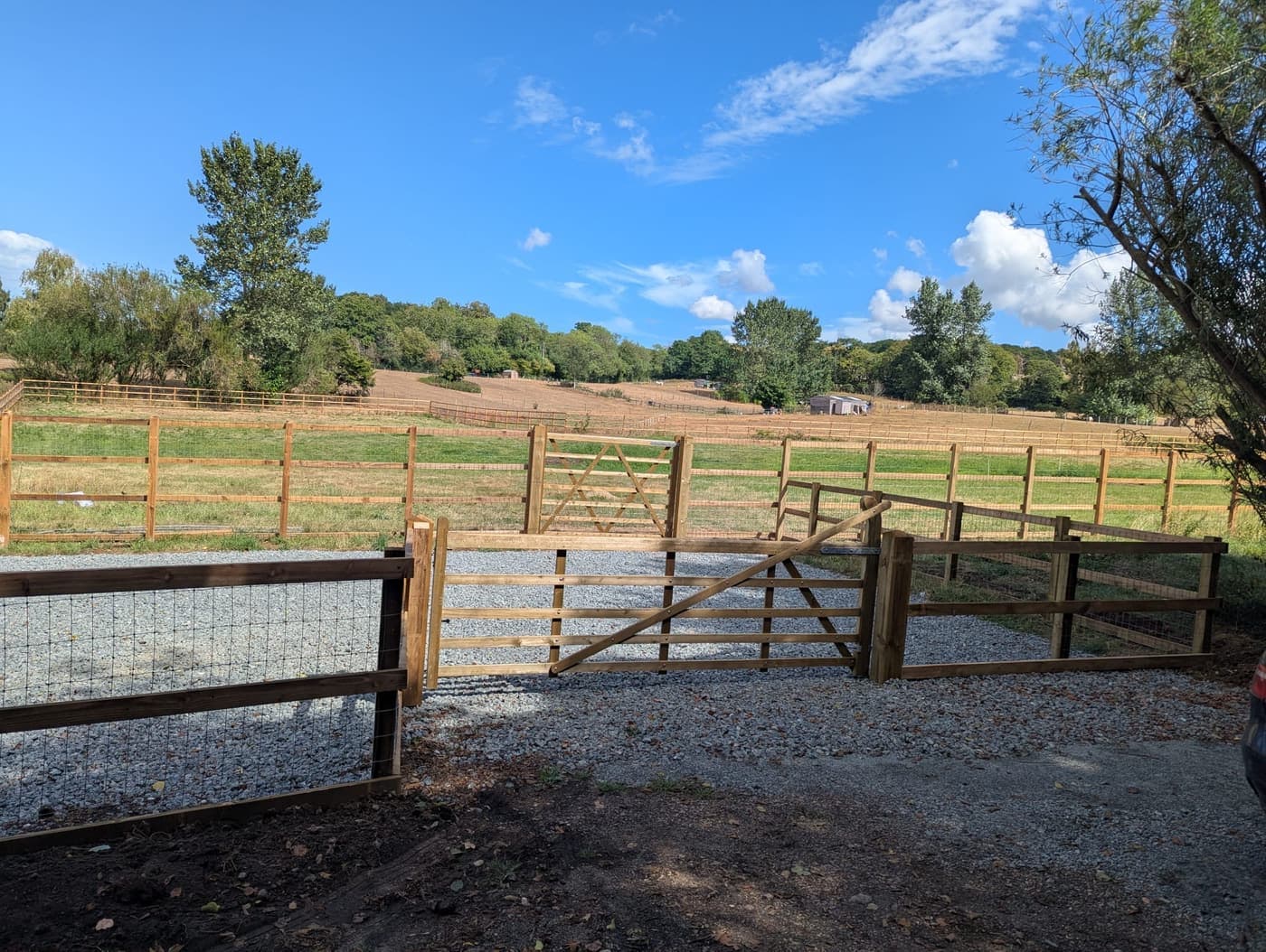 The gravel parking area inside the entrance, with a five bar gate and the field beyond